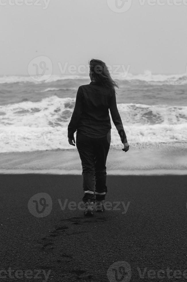 señora que pasa tiempo en la fotografía escénica monocromática de la playa negra foto