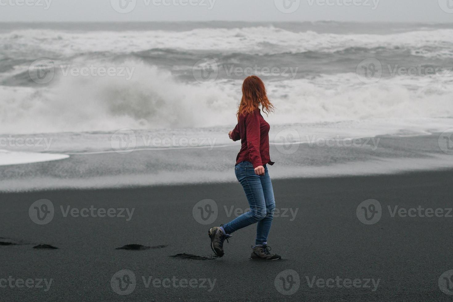 joven turista caminando por la playa vacía de islandia fotografía escénica foto