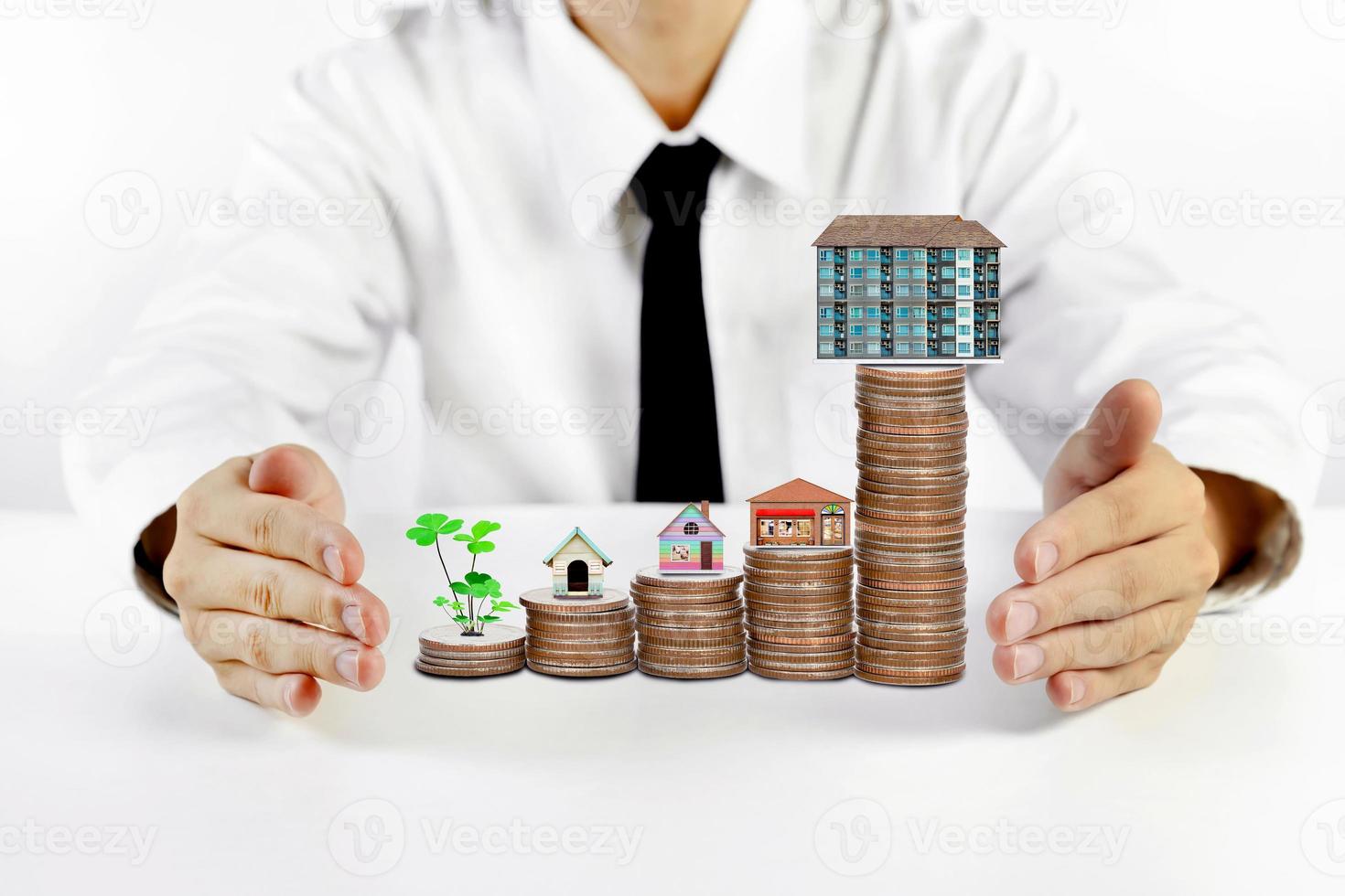 businessman hands protecting house model with piles of coins photo