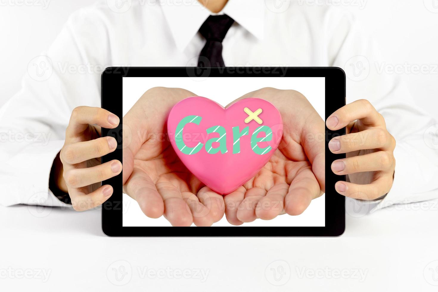 Businessman holding a tablet with heart and write the word care photo