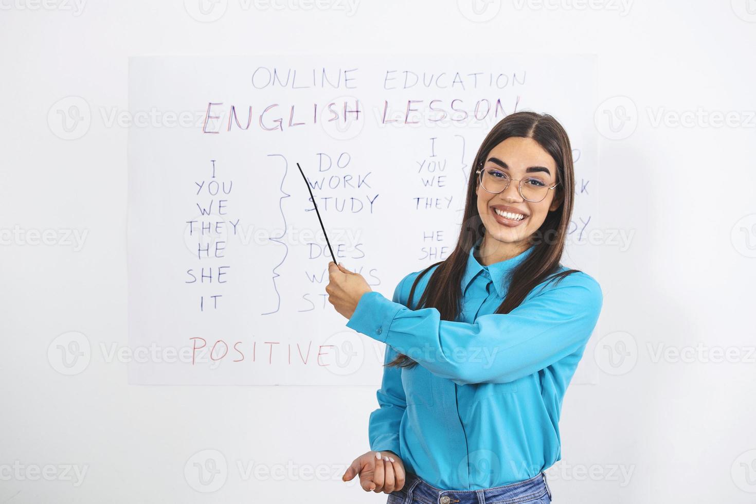 Modern education remotely. Cheerful young woman points to blackboard and explains rules of english online photo