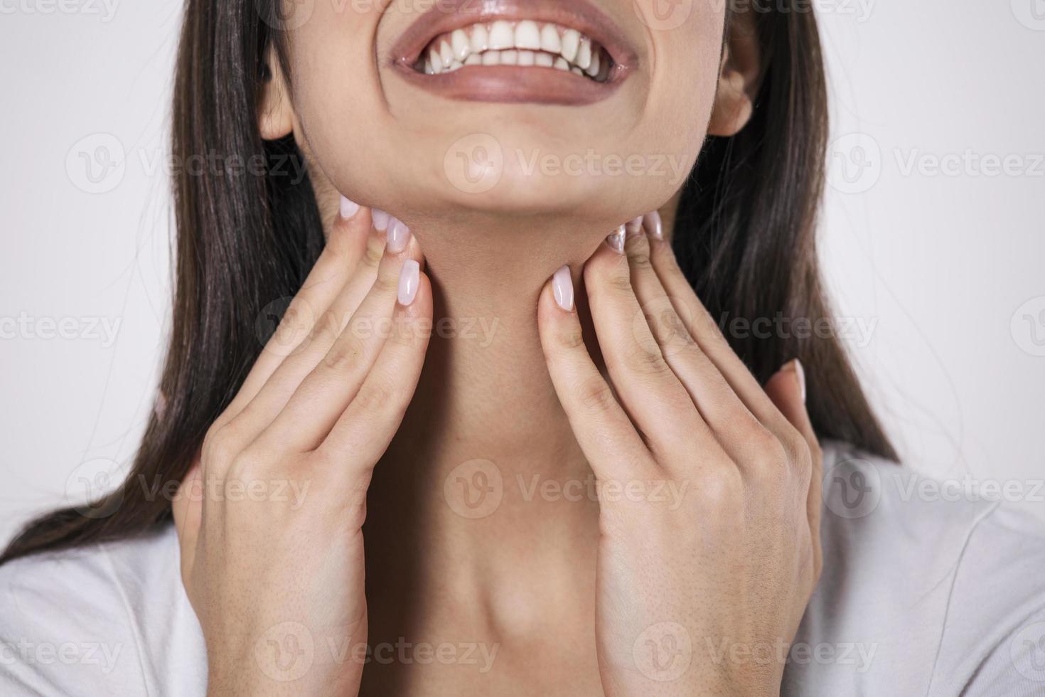 Close up of young woman rubbing her inflamed tonsils, tonsilitis problem, cropped. Woman with thyroid gland problem, touching her neck, girl has a sore throat photo