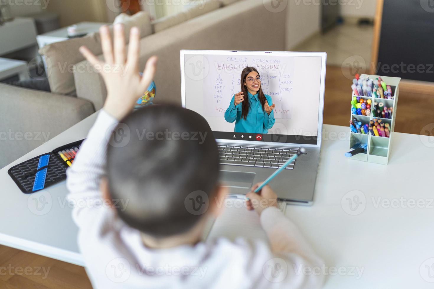 Homeschool little young boy student learning virtual internet online class from school teacher by remote meeting due to covid pandemic. Female teaching english by using whiteboard. photo
