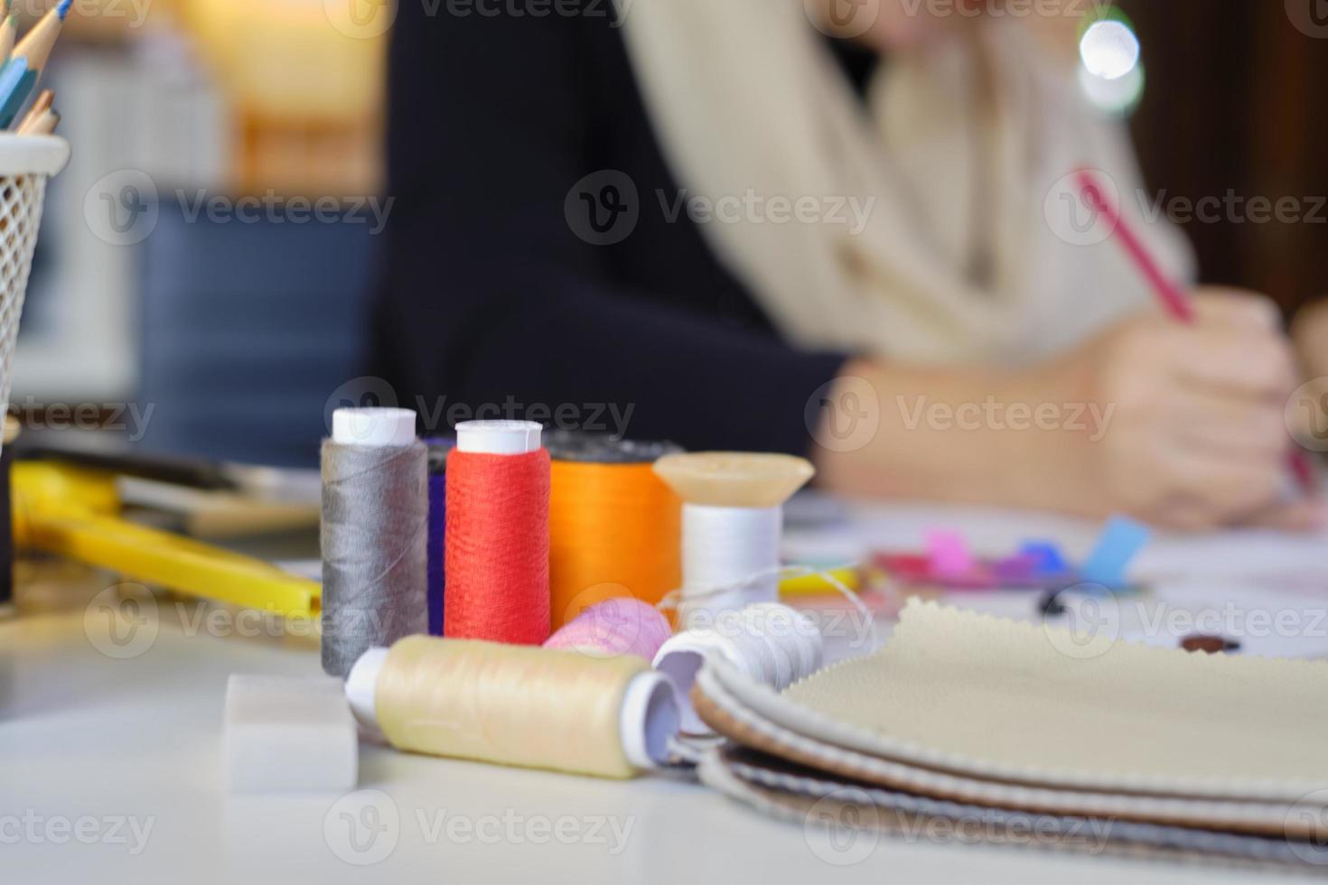 Close-up shot of colorful threads at fashion designer work in a costume studio by idea drawing sketches for fabric sewing in dress design collection, professional boutique tailor stylish occupation. photo