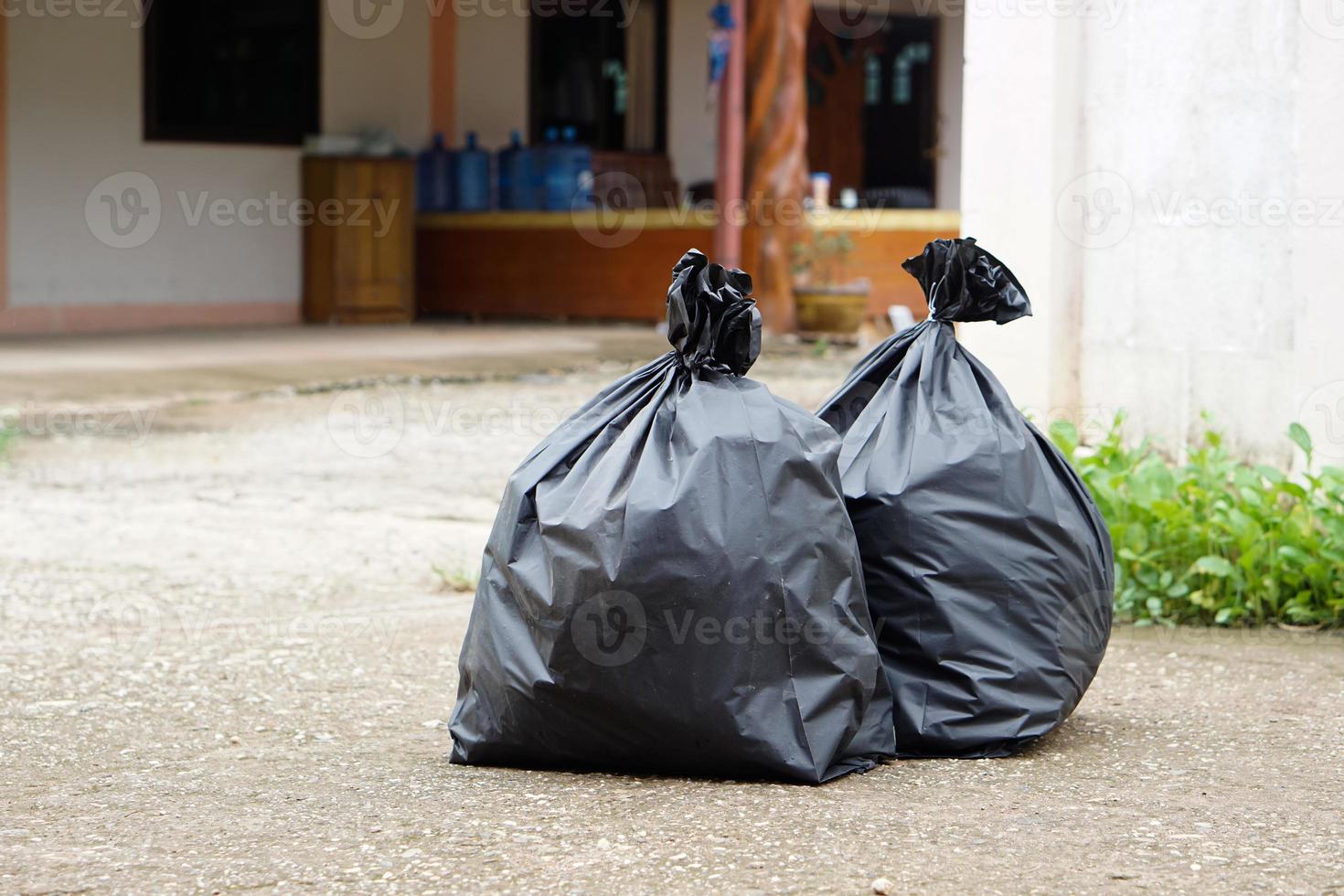 dos bolsas de plástico negras que contienen basura dentro frente a la casa. esperando a que los basureros se los lleven. concepto de gestión de residuos. recogidos para su eliminación. foto