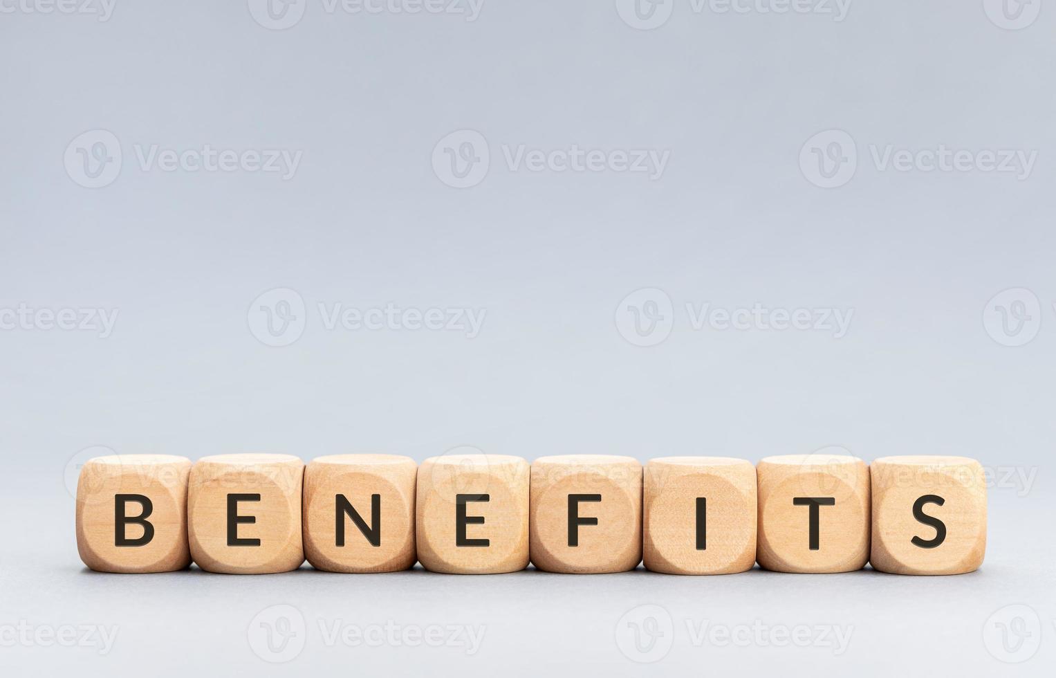 Benefits word on wooden blocks on gray background. Copy space photo