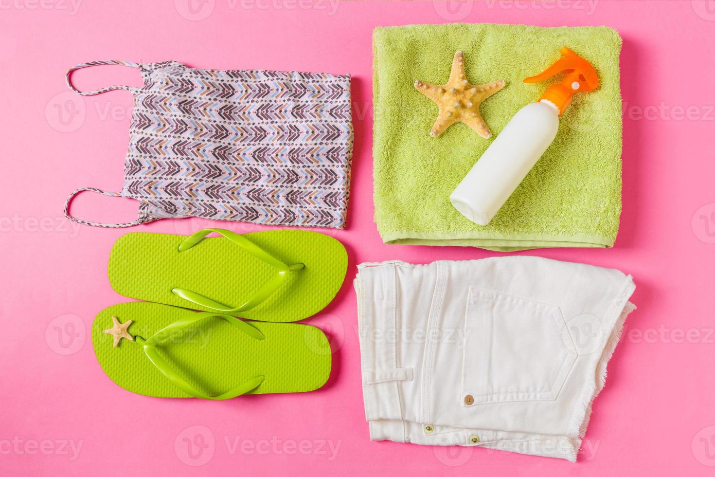 Flat lay composition with green Beach accessories on pink or coral color background. Summer holiday background. Vacation and travel items top view photo