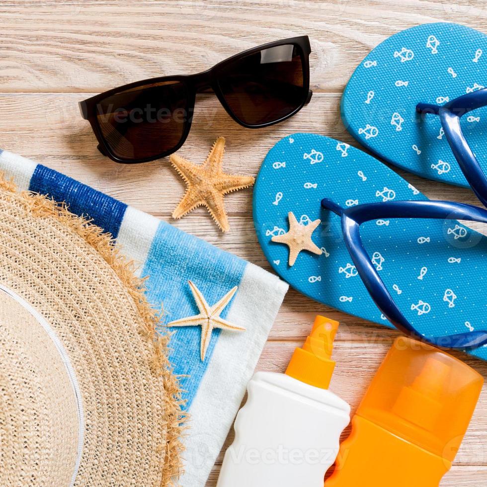 flip flops, straw hat, starfish, sunscreen bottle, body lotion spray on wooden background top view . flat lay summer beach sea accessories background, holiday concept photo