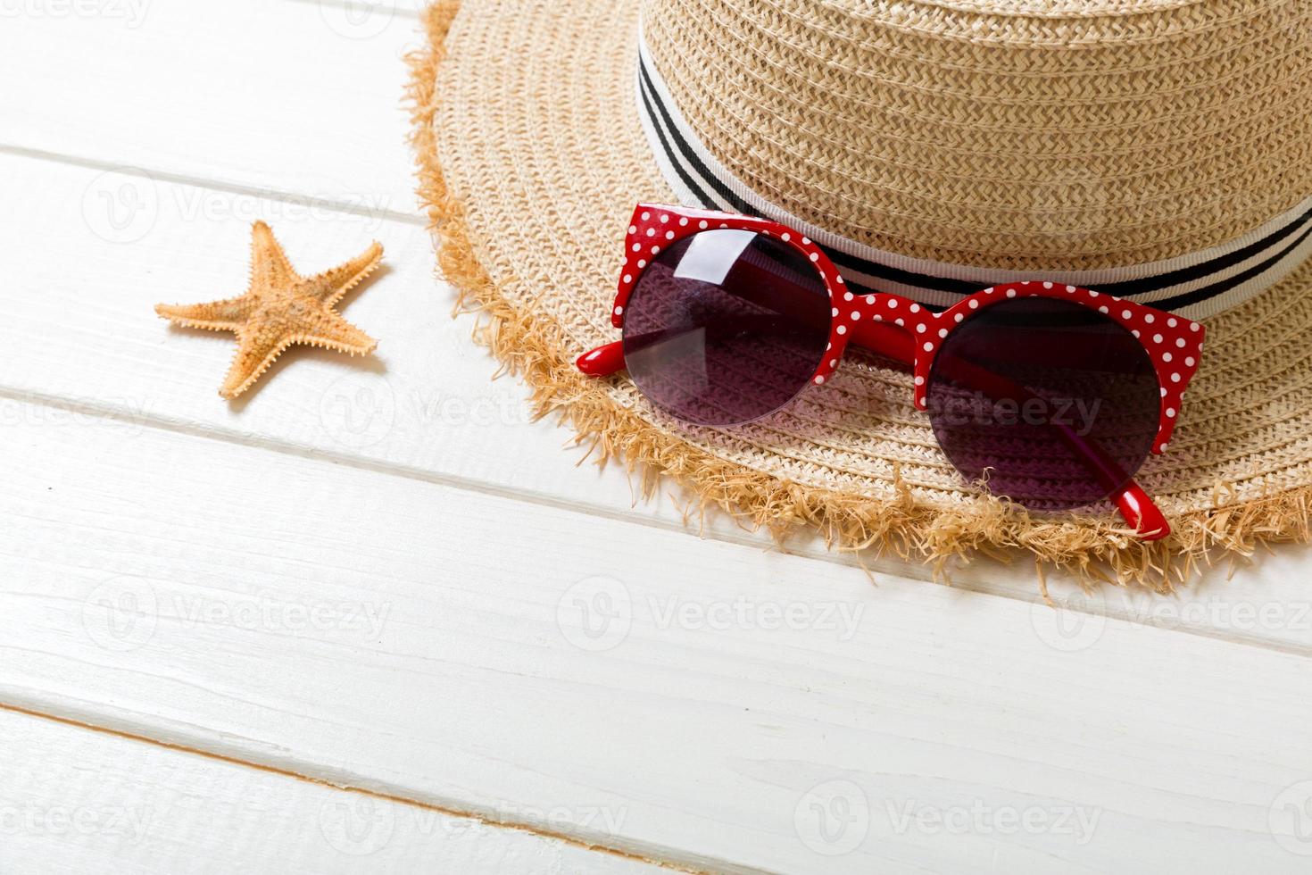 sombrero de paja, gafas de sol y conchas marinas sobre un fondo blanco de madera. vista superior concepto de vacaciones de verano con espacio de copia foto