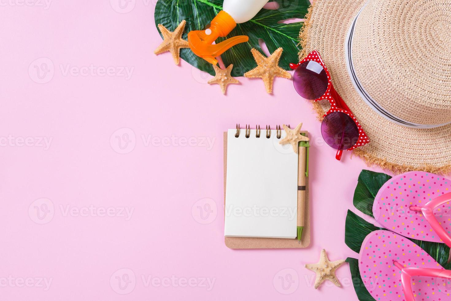 Beach accessories with straw hat, sunscreen bottle and seastar on pink background top view with copy space photo