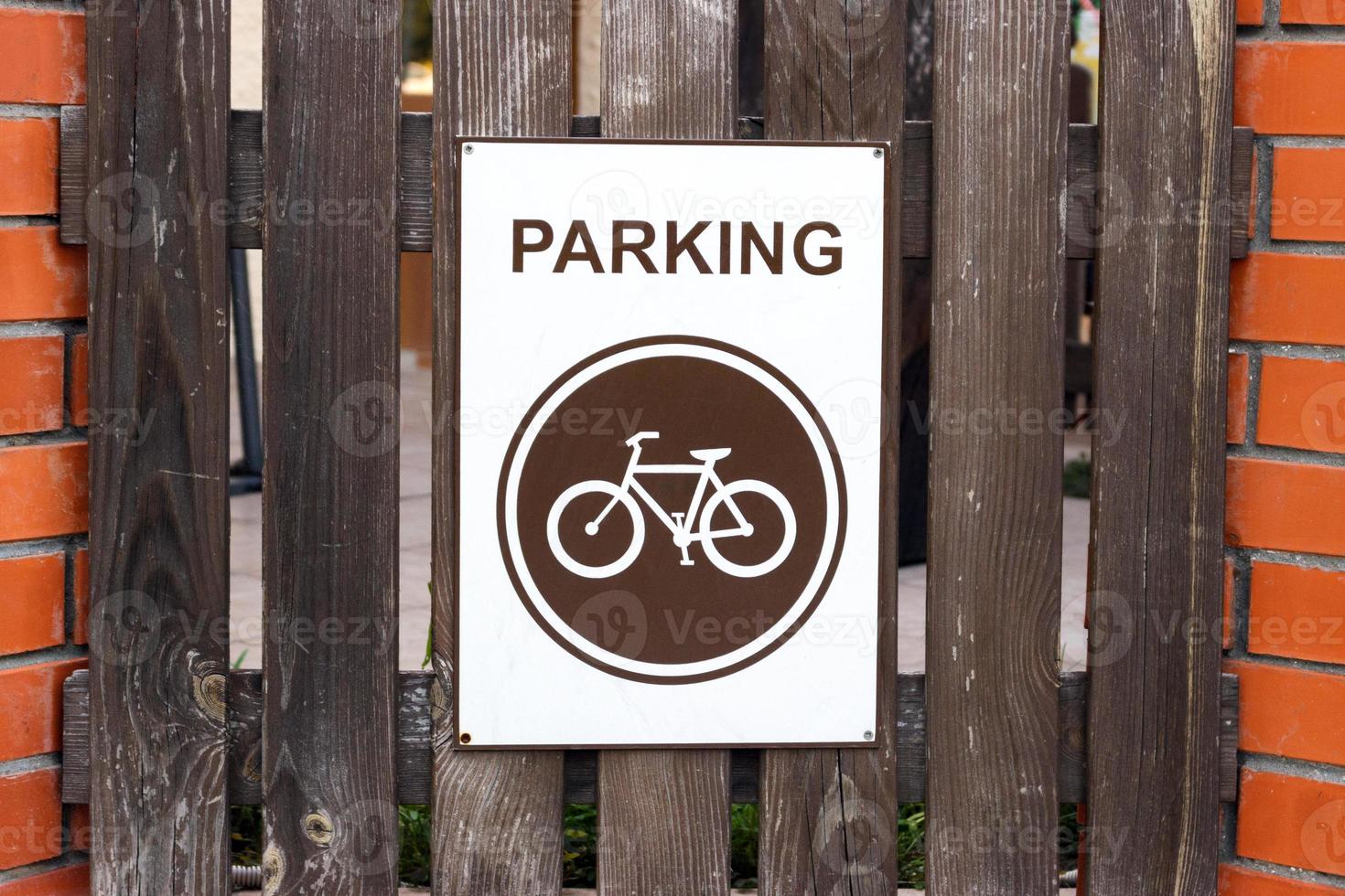 A parking place for bicycles, a sign on a wooden fence photo