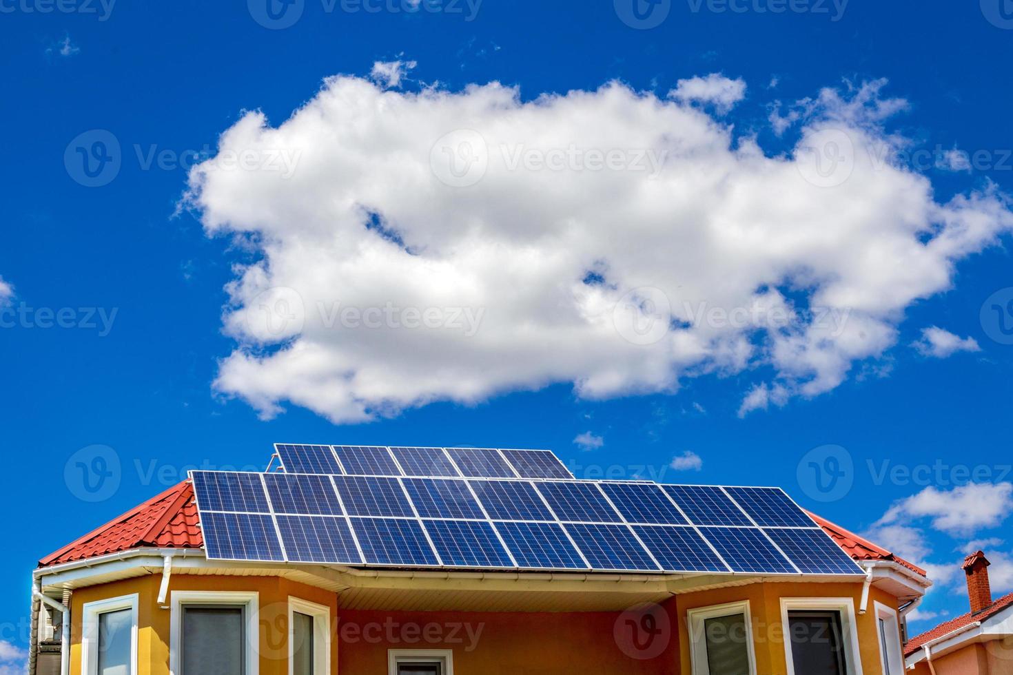 Solar panel on a red roof reflecting the sun and blue sky photo