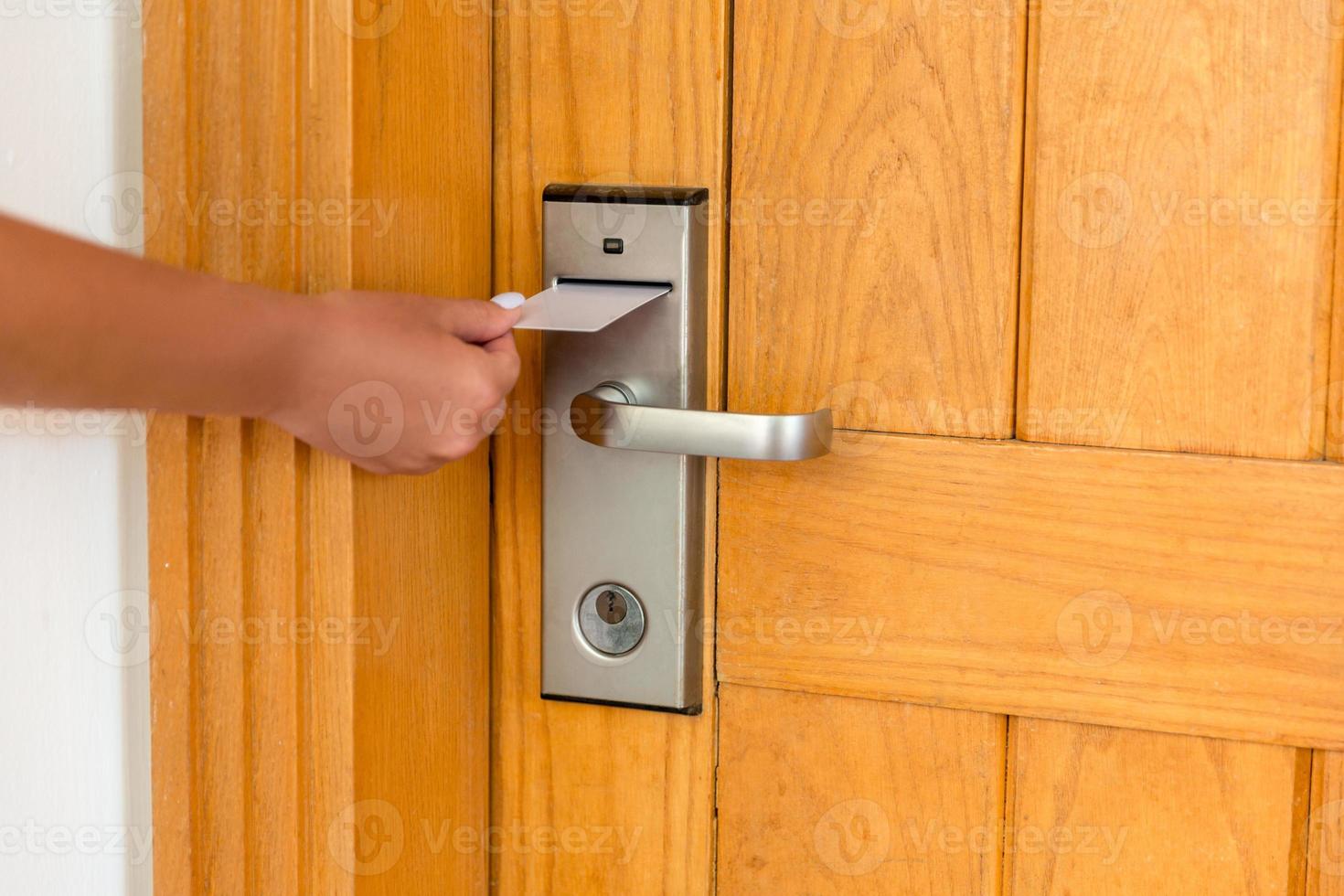 mano femenina colocando y sosteniendo el interruptor de la tarjeta de llave magnética para abrir la puerta de la habitación del hotel foto