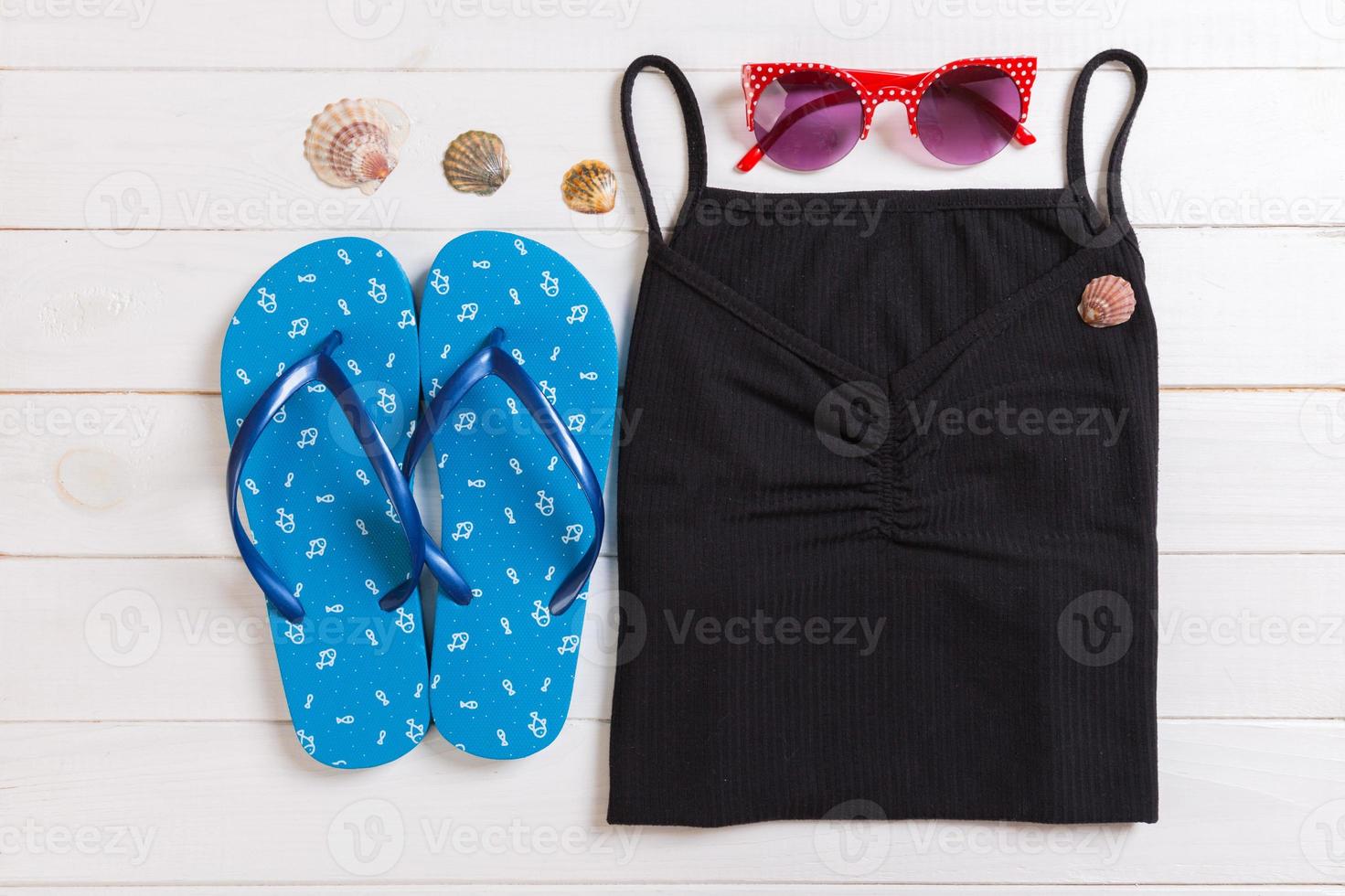 Summer accessories with t-shirt, seashells and flip fops on white wooden background top view flat lay photo