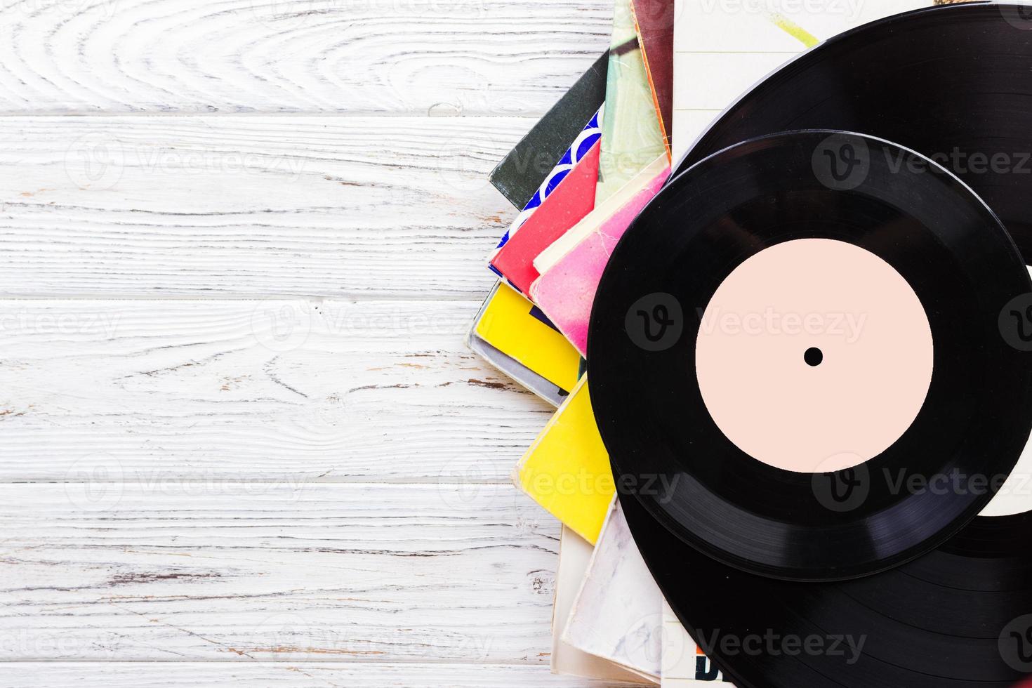 selective focus of selective focus image of records stack with record on top over wooden table. vintage filtered photo