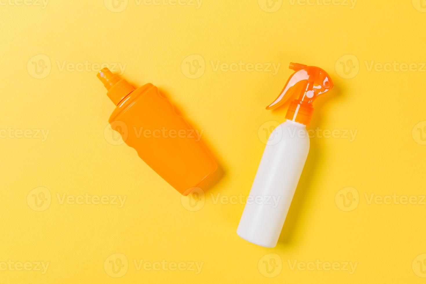 flat lay concept of summer travel vacation. Sunscreen bottle mock up on yellow background top view with copy space photo