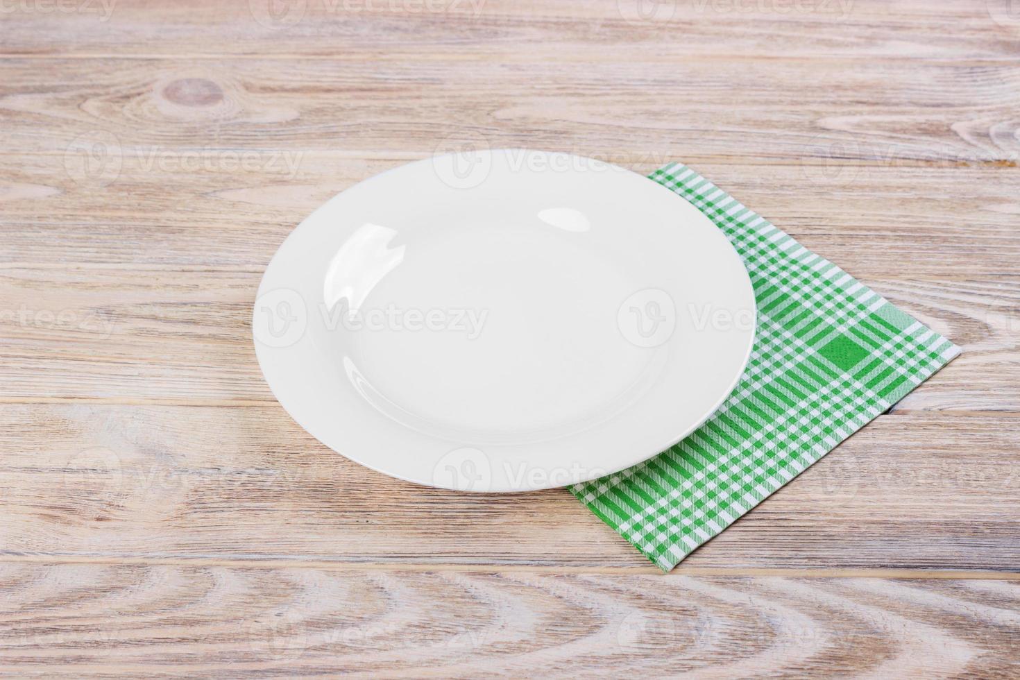 plato blanco vacío sobre mesa de madera, servilleta verde foto