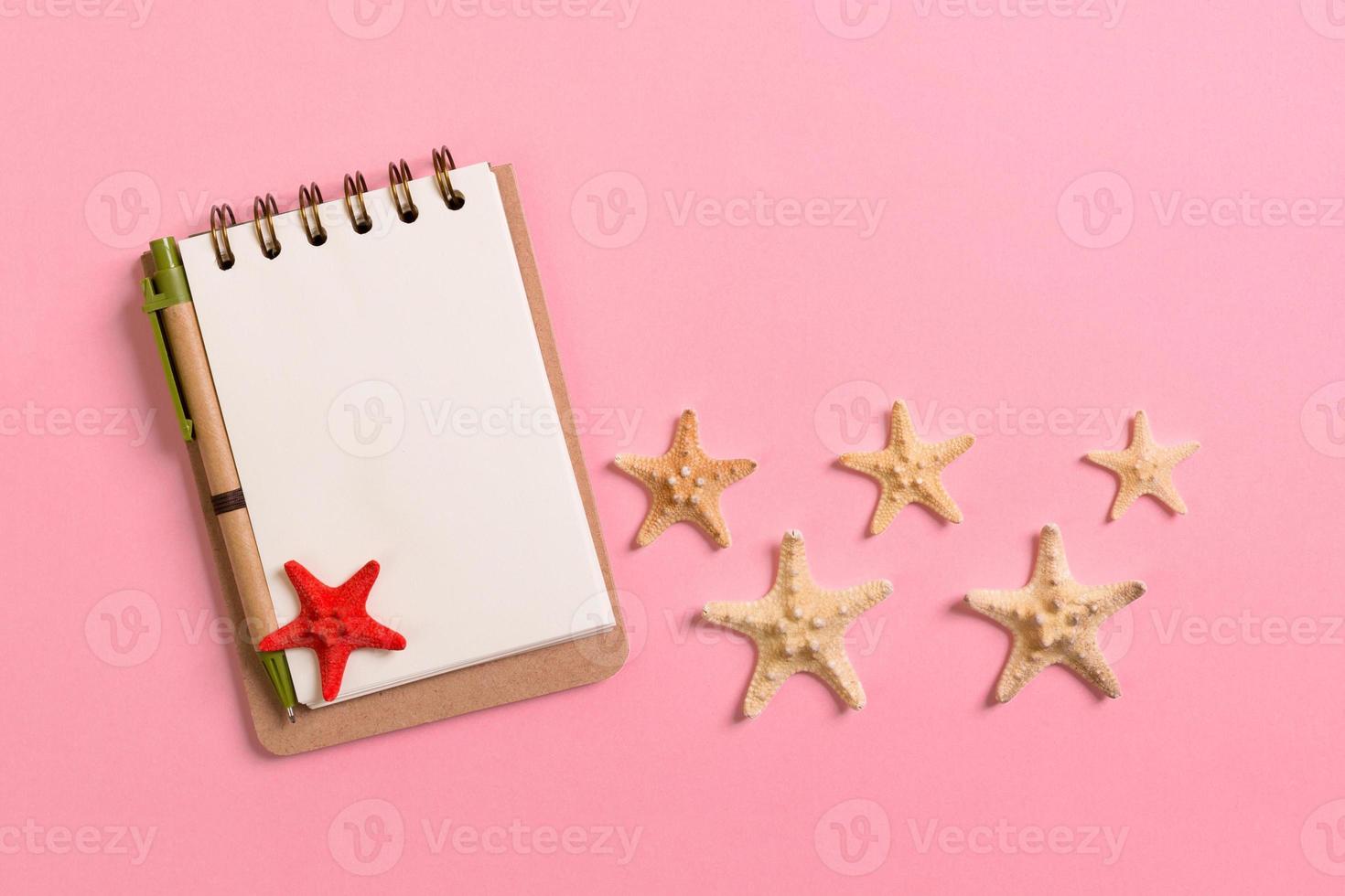 blank note book with starfish or seashells on a pink background , summer vaction concept photo