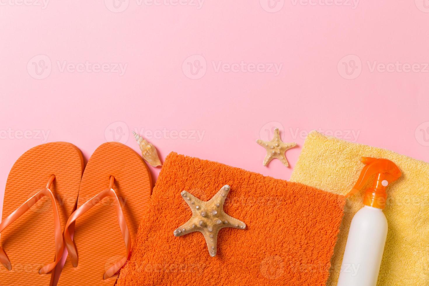 Top view of Beach flat lay accessories. sunscreen bottle with seashells, starfish, towel and flip-flop on Colored background with copy space photo