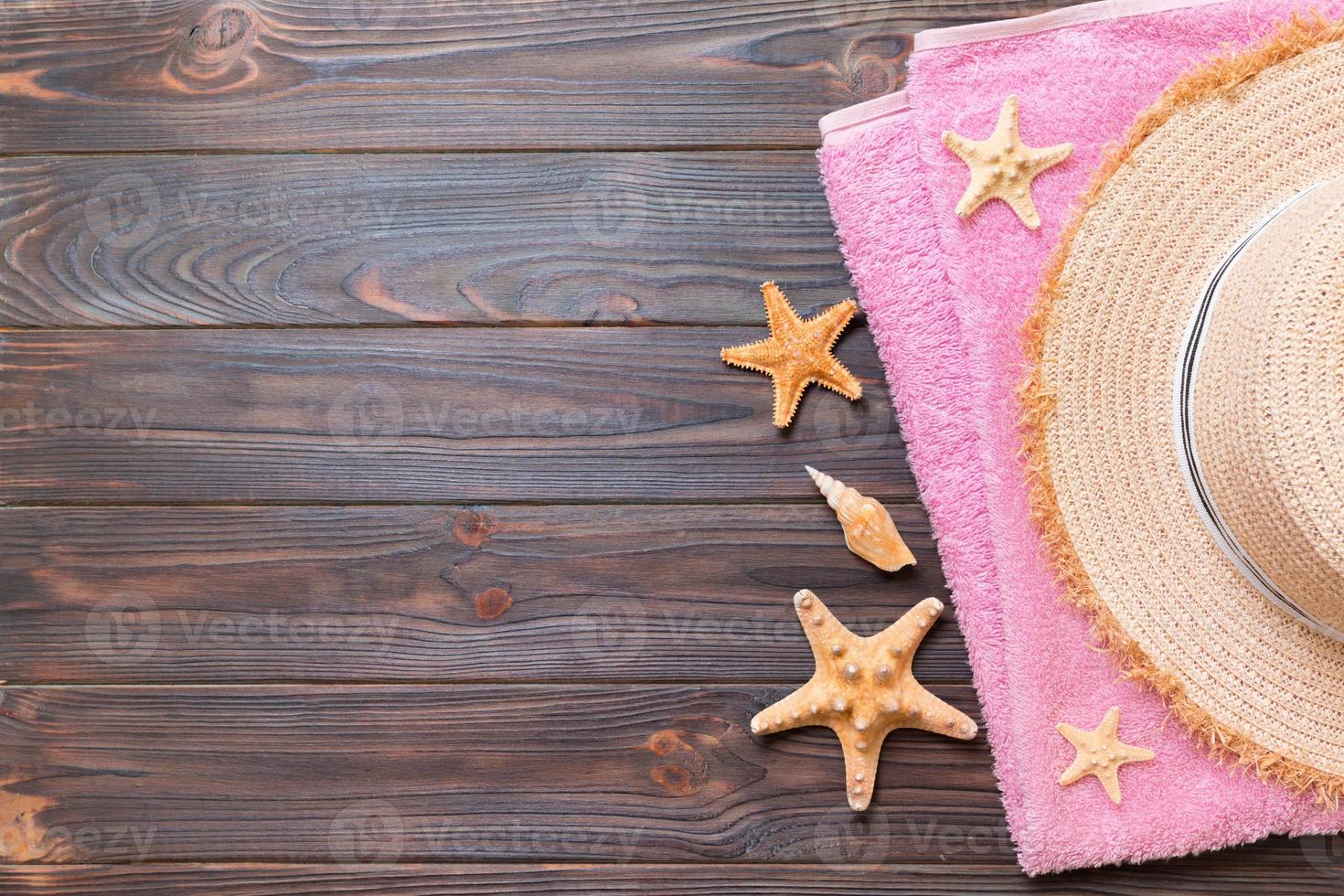 Straw hat, pink towel and starfish On a dark wooden background. top view summer holiday concept with copy space photo
