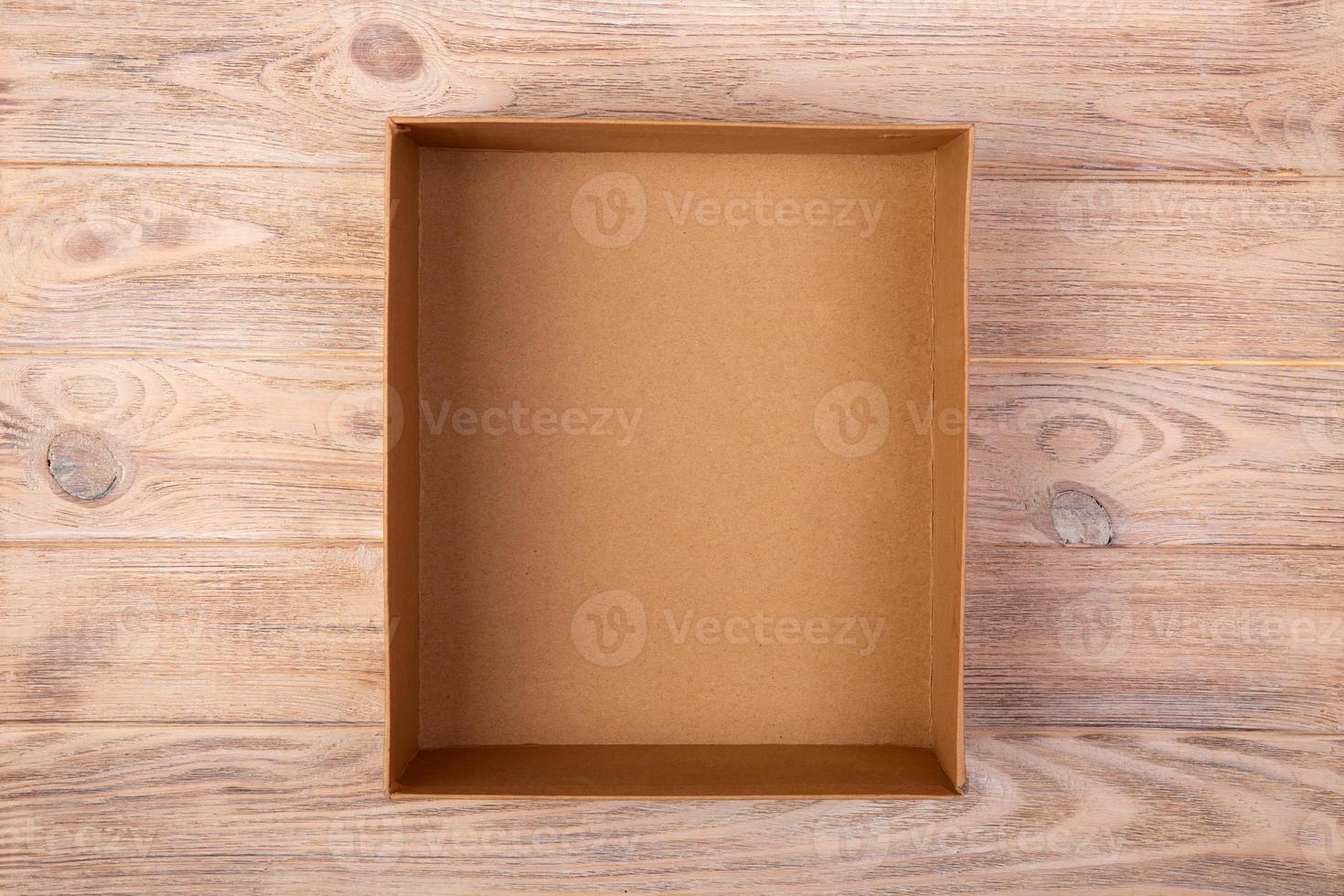 Opened cardboard box on wooden background. top view photo