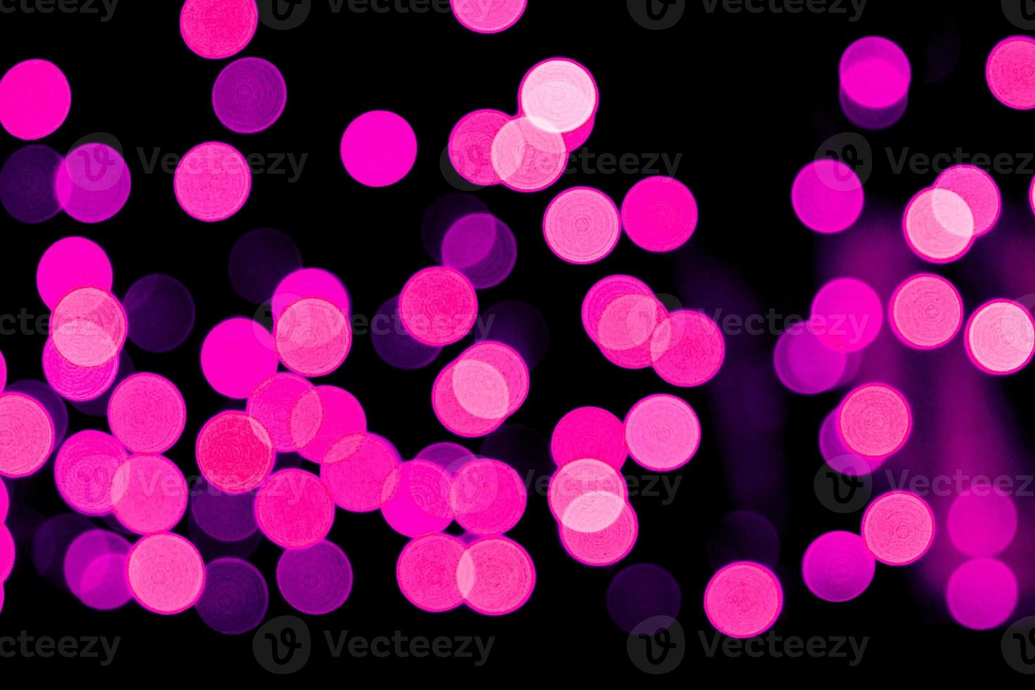 Unfocused abstract purple bokeh on black background. defocused and blurred many round light photo