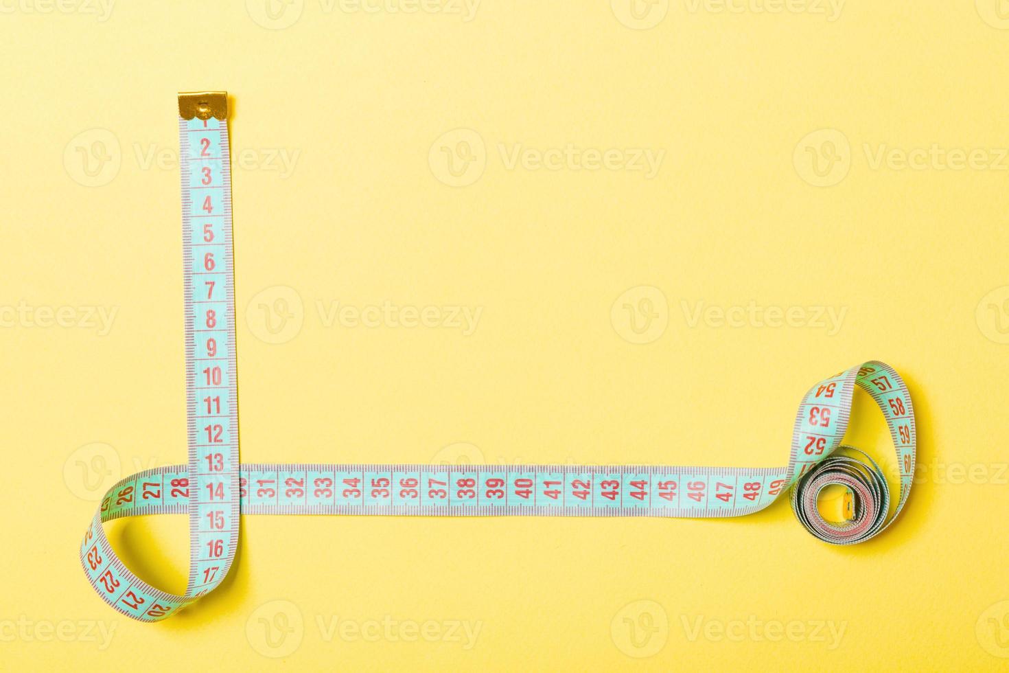 Top view of measure tape in the form of frame on yellow background. Balanced eating concept with copy space photo