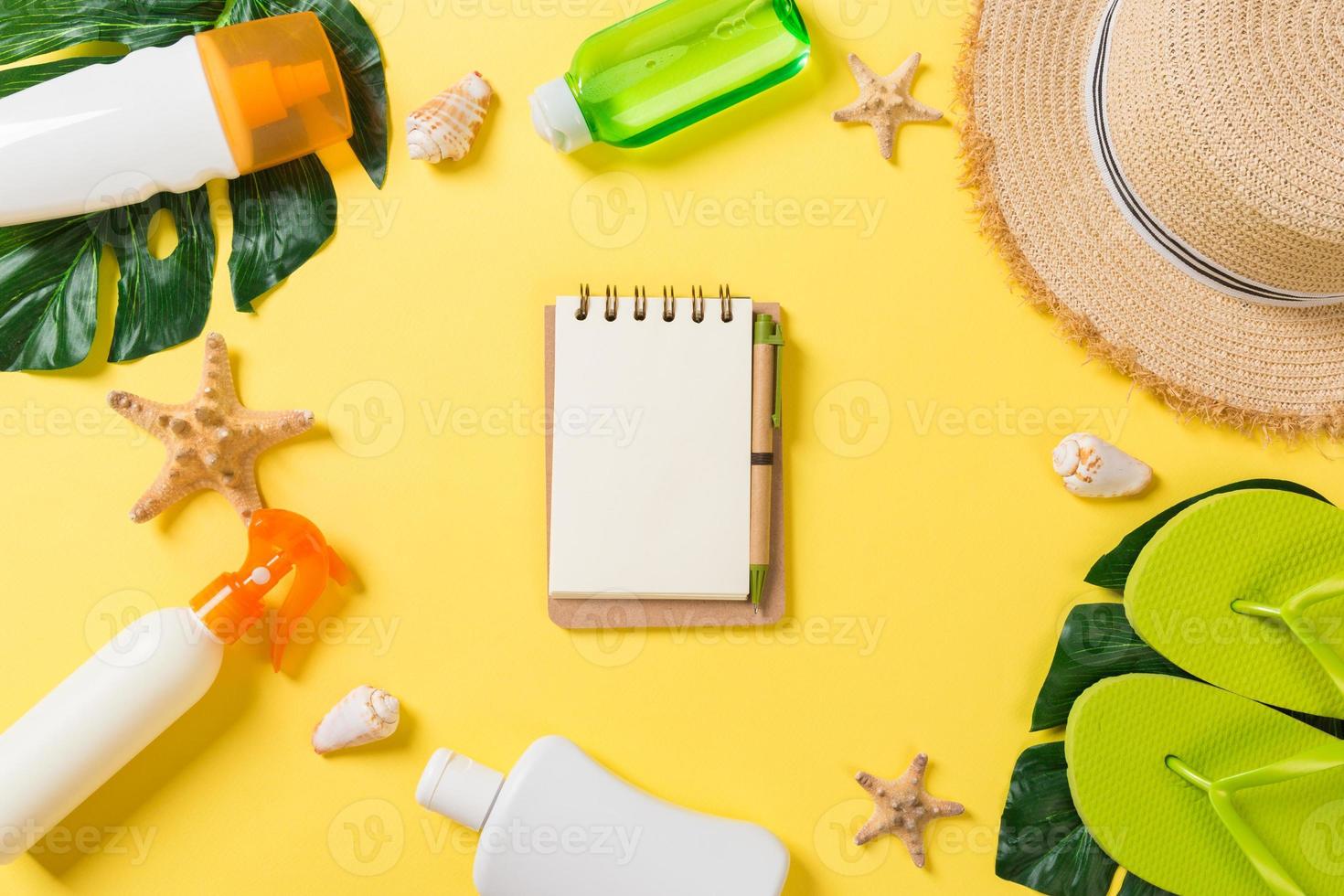 Beach accessories with straw hat, sunscreen bottle and seastar on yellow background top view with copy space photo