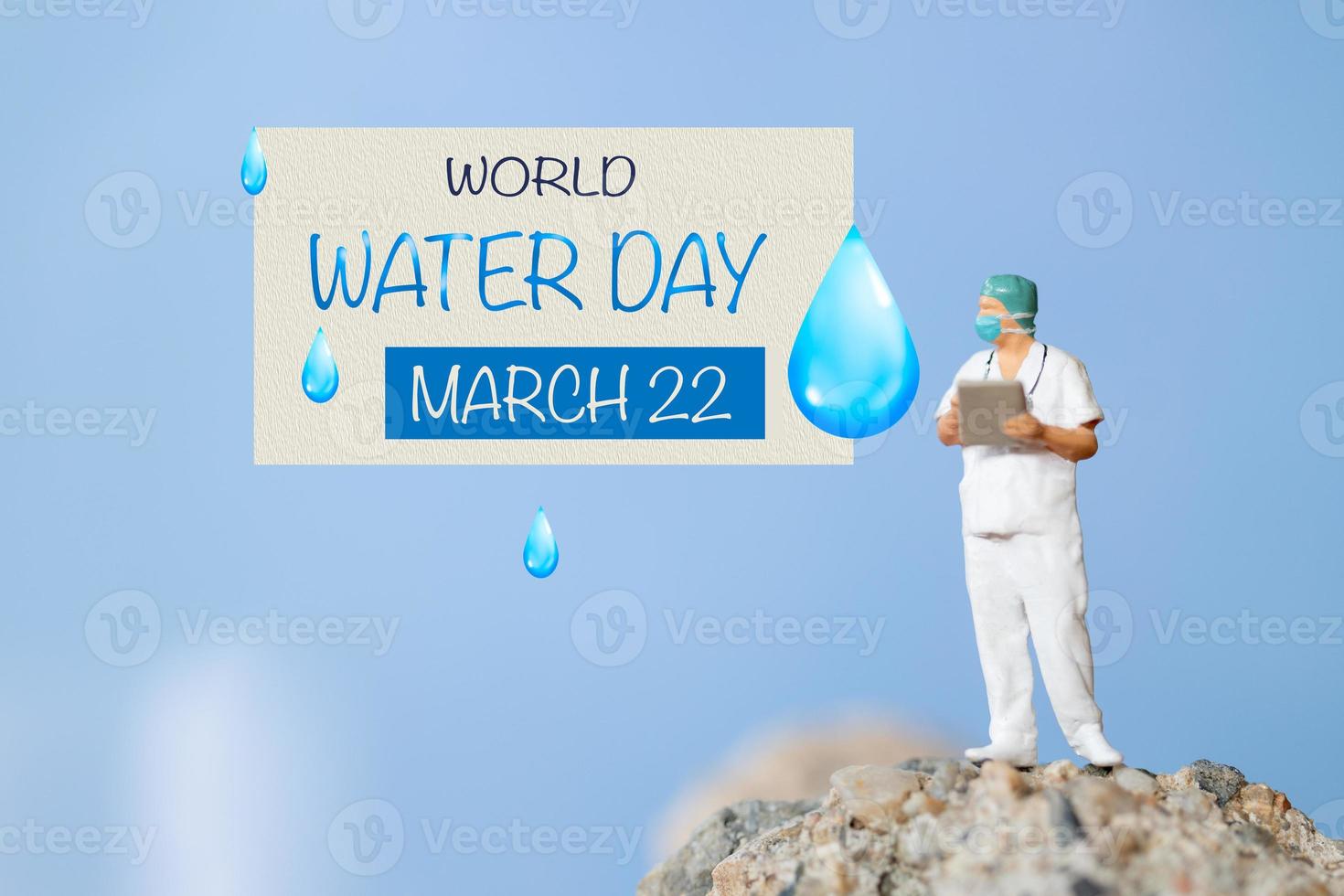 Miniature people Doctor checking text World Water Day on paper while standing atop a rock photo