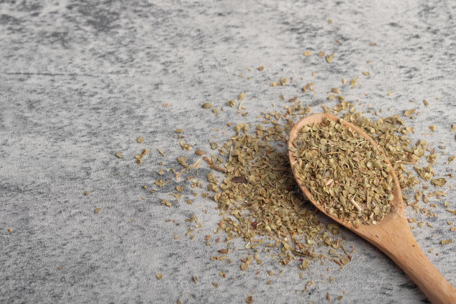 oregano in wooden spoon on gray background photo