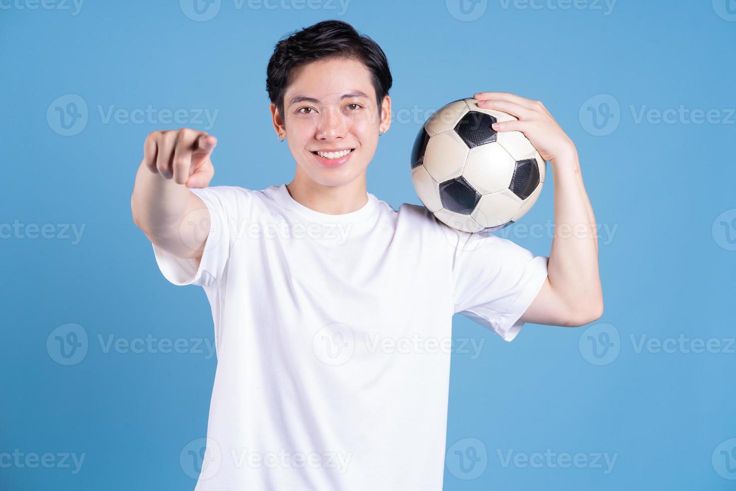 Young Asian man holding ball on background photo