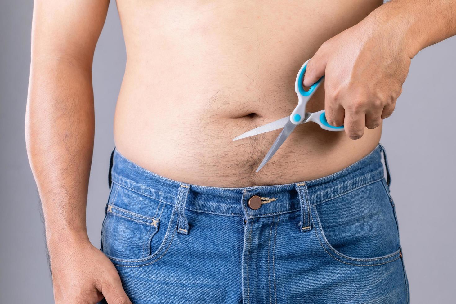 Portrait man using scissors to cutting body hair. Studio shot on grey photo