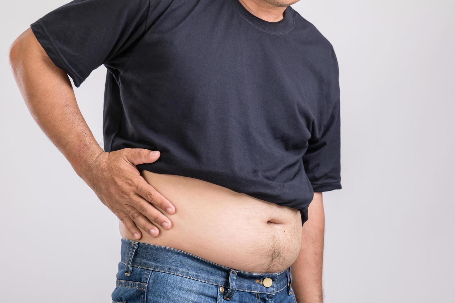 Body pain, hip pain or effect from liver problem  Fat man using his hand and pressing on hip position. Studio shot on grey photo