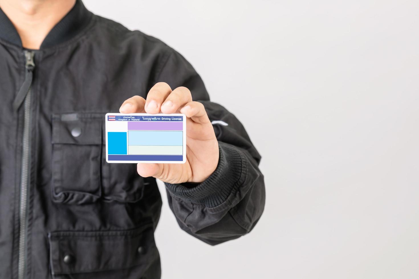 Portrait rider in black jacket holding and show blank Thailand driving licence. Over 400cc motorcycle in Thailand need especially licence. Studio shot isolated on grey photo