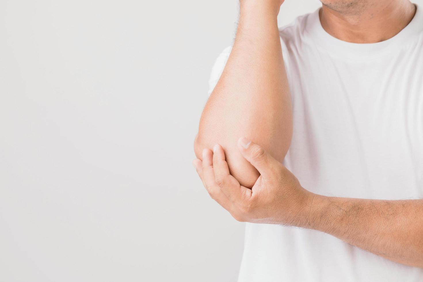 primer plano hombre sujetando el codo y sintiendo dolor. foto de estudio aislada sobre fondo gris con espacio para copiar texto