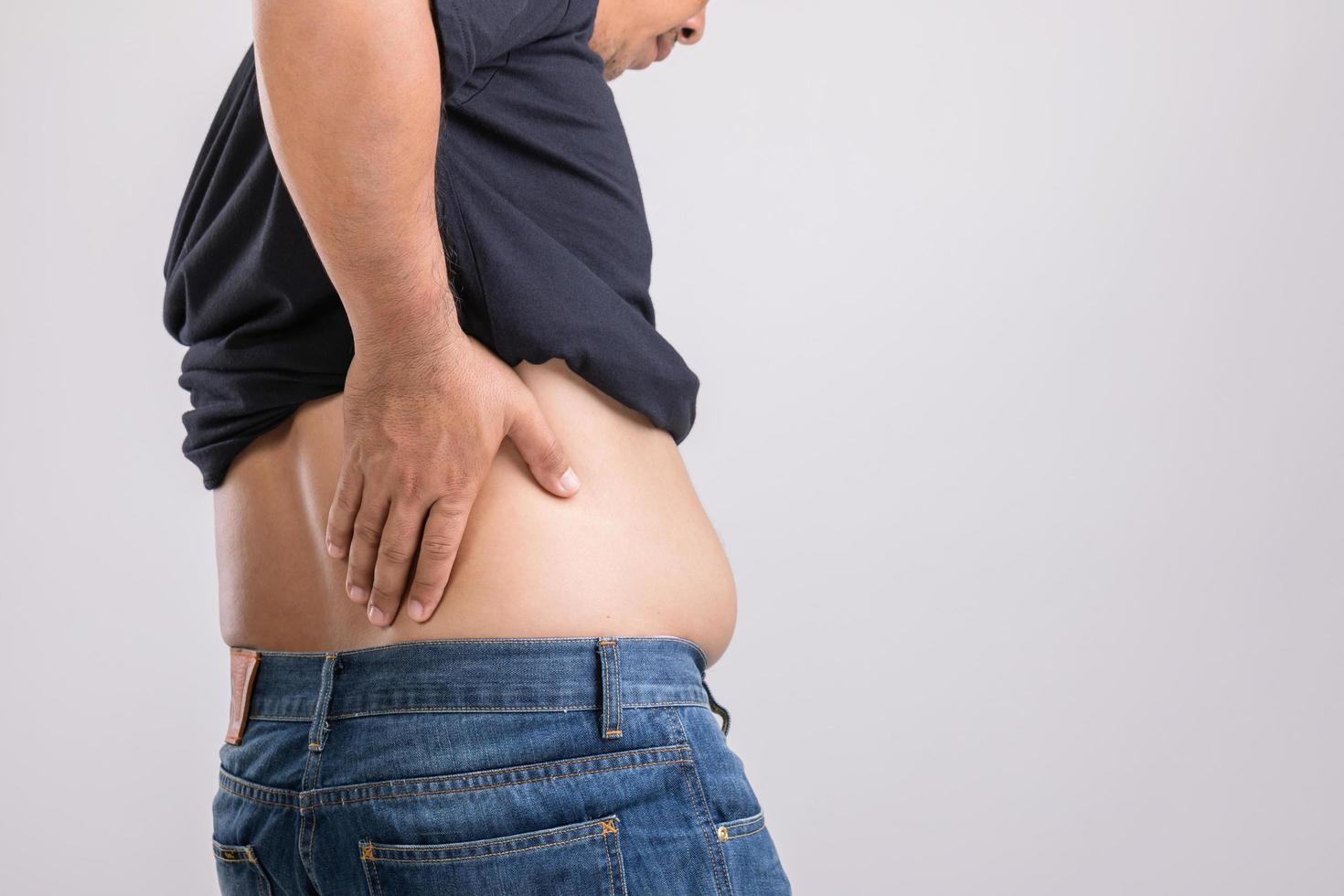 dolor corporal, dolor de cadera o efecto del problema hepático hombre gordo usando su mano y presionando la posición de la cadera. foto de estudio en gris