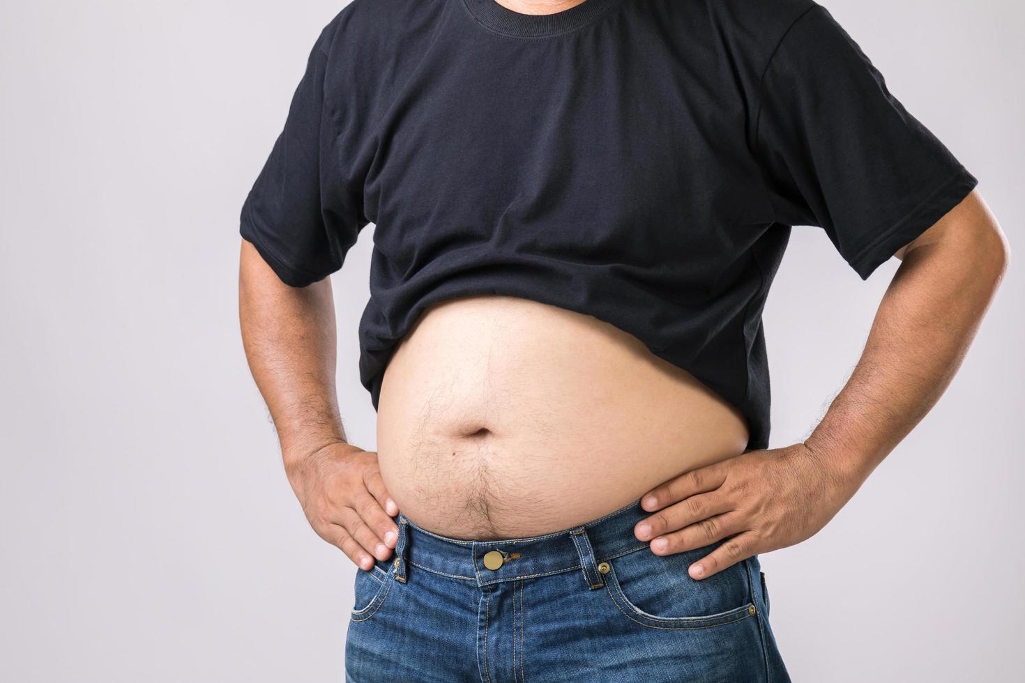 Medical check up concept  Fat people showing his big belly. Used for liver problem or Obesity concept. Studio shot on grey photo