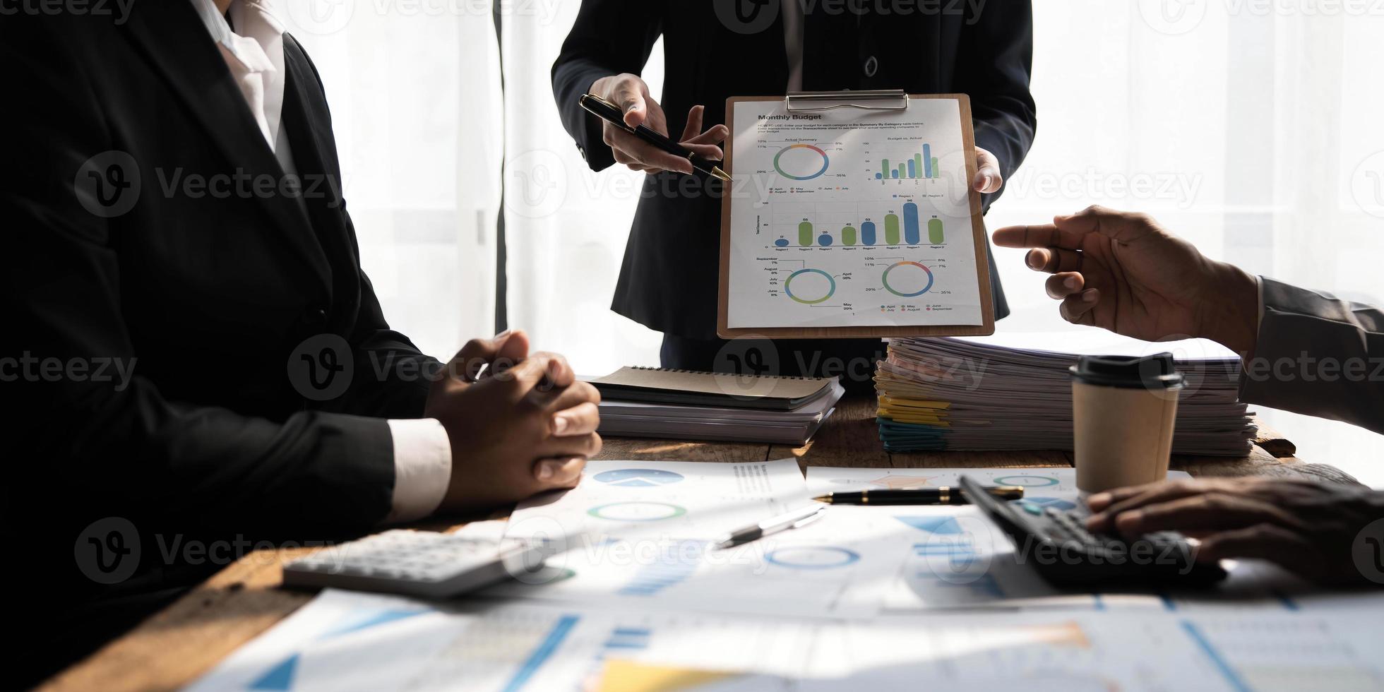 gente de negocios reunida usando computadora portátil, calculadora, cuaderno, papel gráfico del mercado de valores para planes de análisis para mejorar la calidad el próximo mes. conferencia discusión concepto corporativo foto