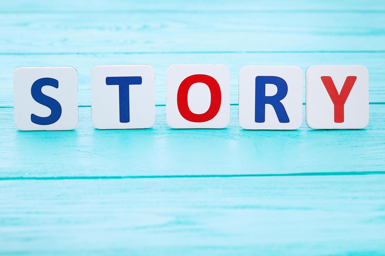 Word story on blue wooden table. Selective focus and copy space photo