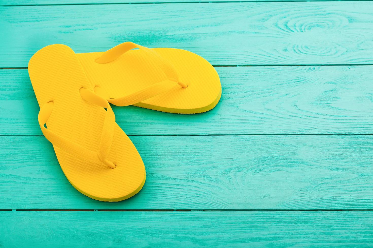 Yellow flip flops on blue wooden background. Summer holidays. Top view. Mock up. Copy space photo