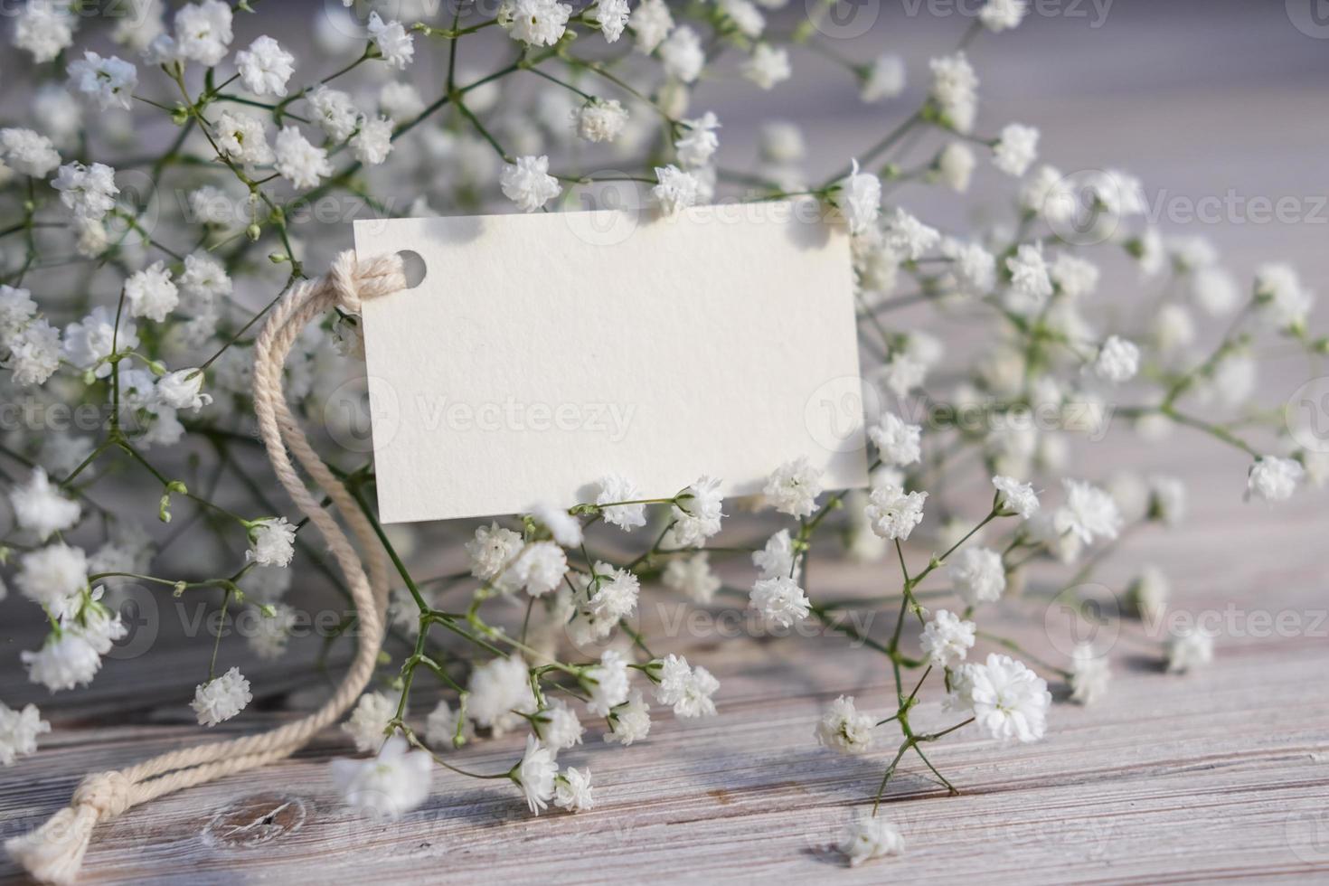 White flowers and blank white card for text. Mockup tag. Postcard photo