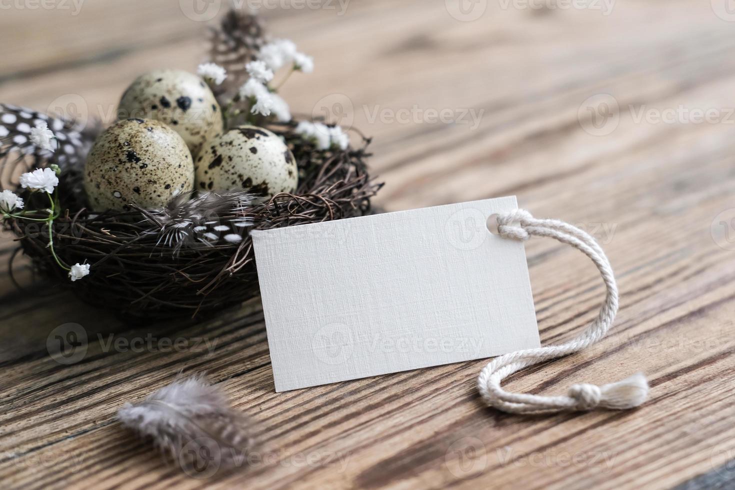 Nest with quail eggs and blank white card for text. Mockup tag. Easter card. Easter decor in rustic style. Natural Eco Friendly Easter Decor photo