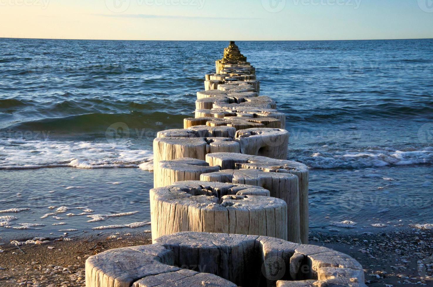 Groynes jut into the horizon in the Baltic Sea. Breakwater at the sea photo