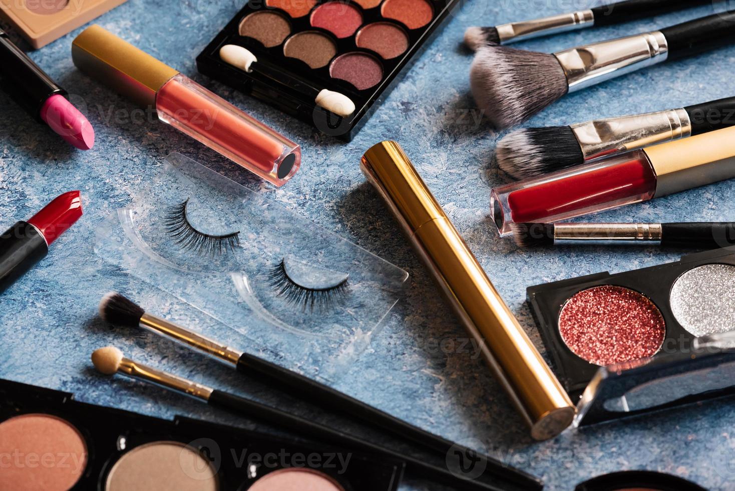 Various makeup products, brushes blue background. photo