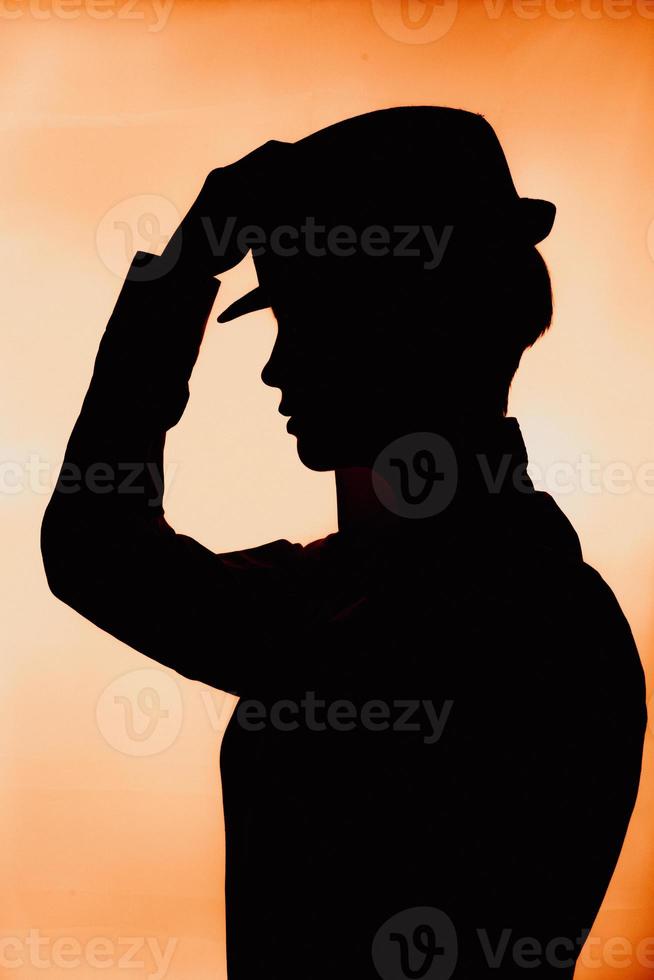 a silhouette of a girl in a hat with a cigarette. photo with the thrown grain