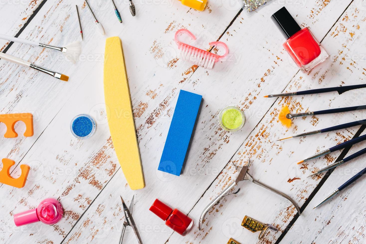 conjunto de herramientas de manicura y esmaltes de uñas sobre un fondo de madera blanca. foto