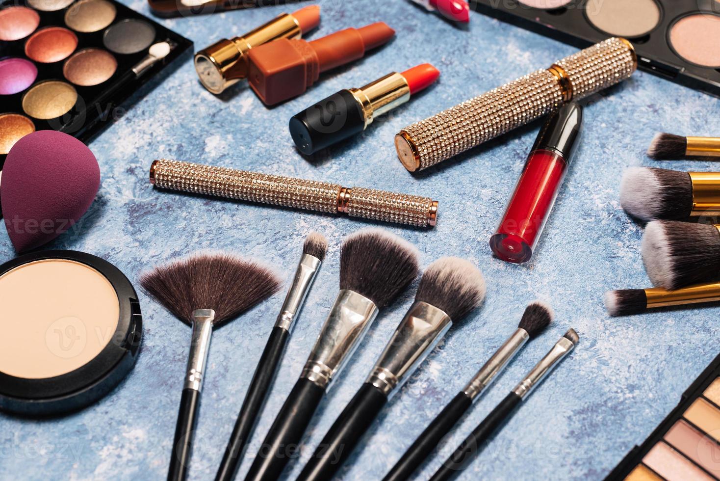 Various makeup products, brushes on blue background photo