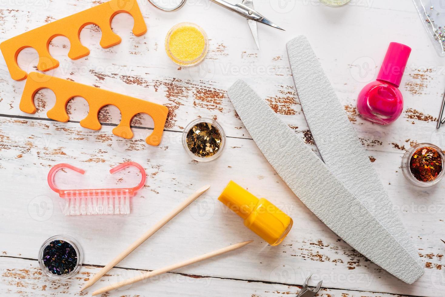 set of manicure tools and nail polishes on a white wooden background. photo