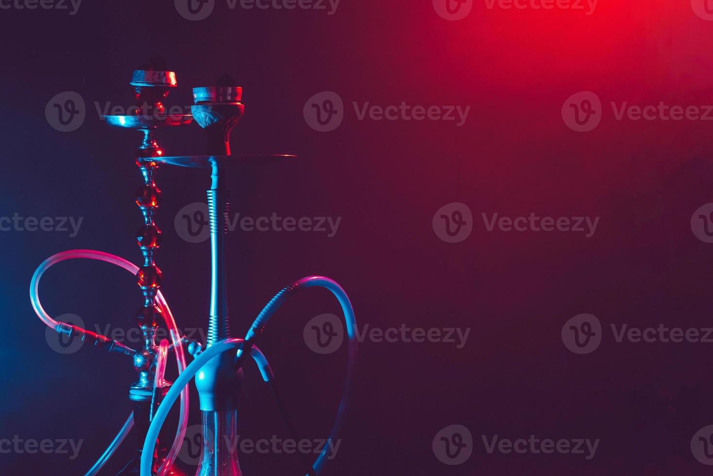 Modern hookah, shisha on a black background with colored lighting and smoke. Place for your text photo