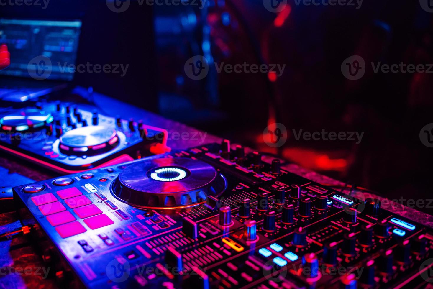 consola de dj para mezclar música con gente borrosa bailando en una fiesta de discoteca foto